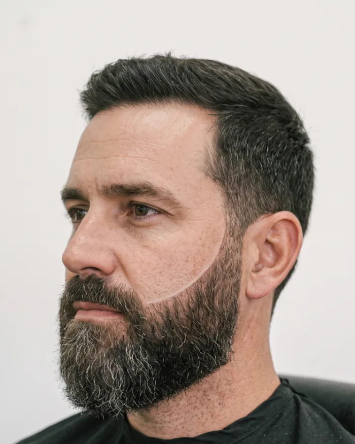 A sharp beard line-up on a full dark beard