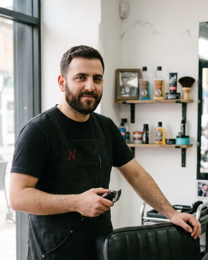 Marco, a barber in his early thirties, beside his chair